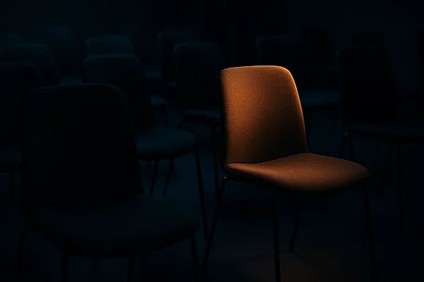 Über die Website finden Ein warm beleuchteter Stuhl hebt sich von dunklen Stühlen ab — Sinnbild für eine offene Stelle, Recruiting über die Website